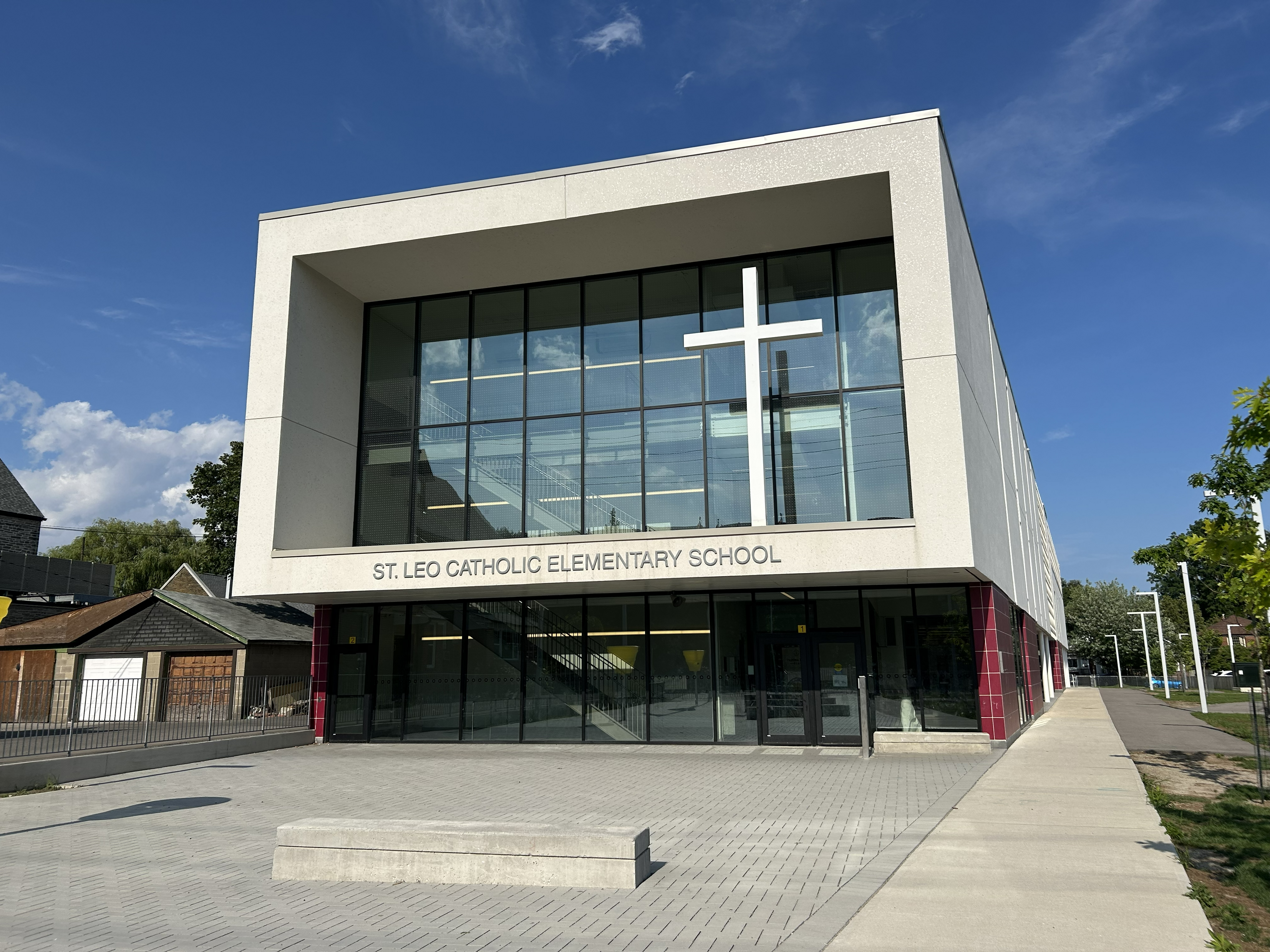 An image of the St. Leo Catholic School building, surrounded by houses on the left side and trees and the school grounds on the other side