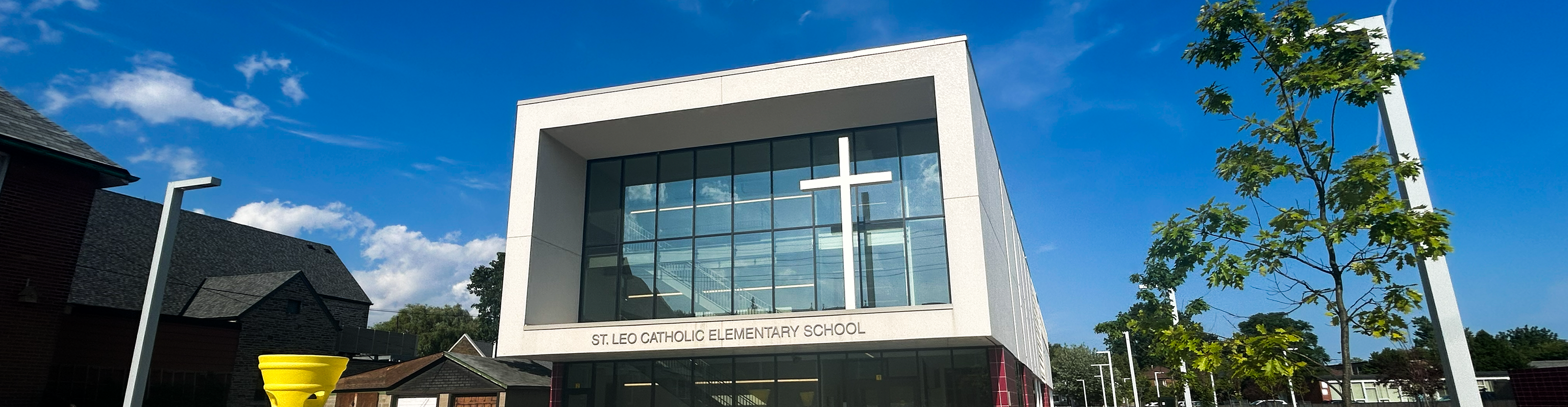 An image of the St. Leo Catholic School building, surrounded by houses on the left side and trees and the school grounds on the other side