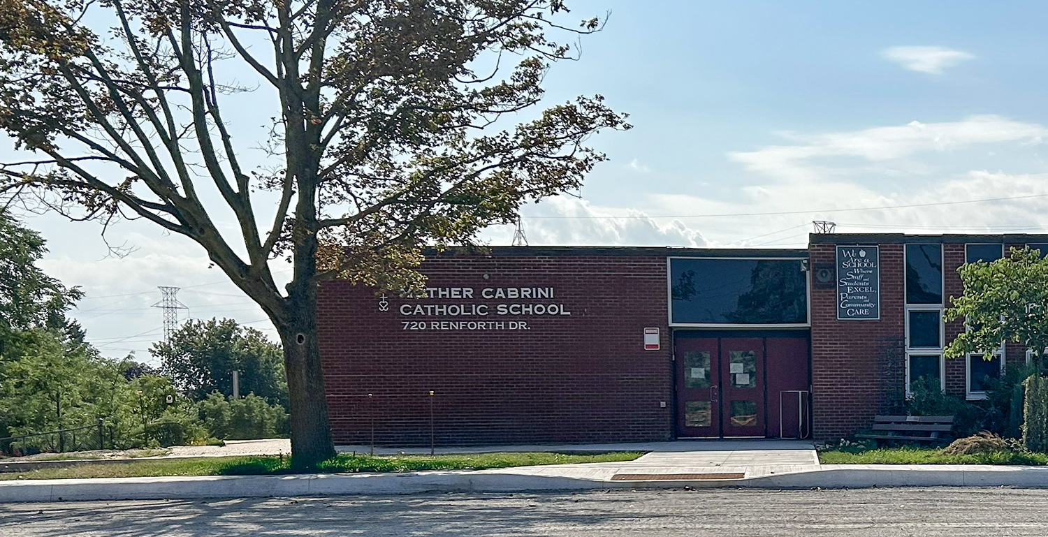 The front of the Mother Cabrini Catholic School building, showing the red brick building against a sunny blue sky