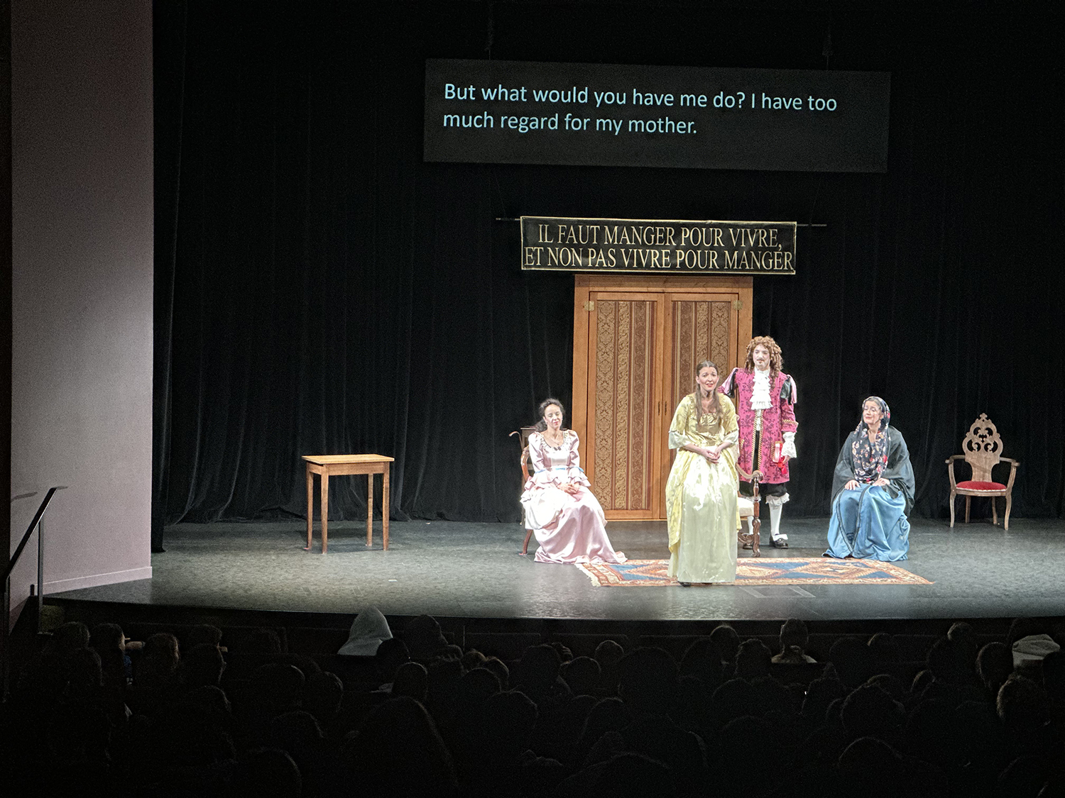 Photo of a performance on stage of people in older French outfits