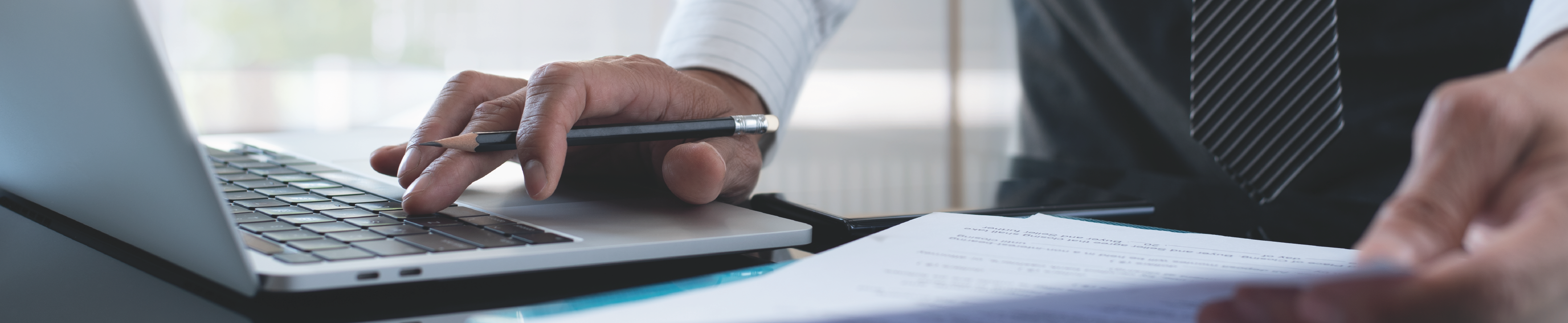 A person using a laptop while reviewing a document.