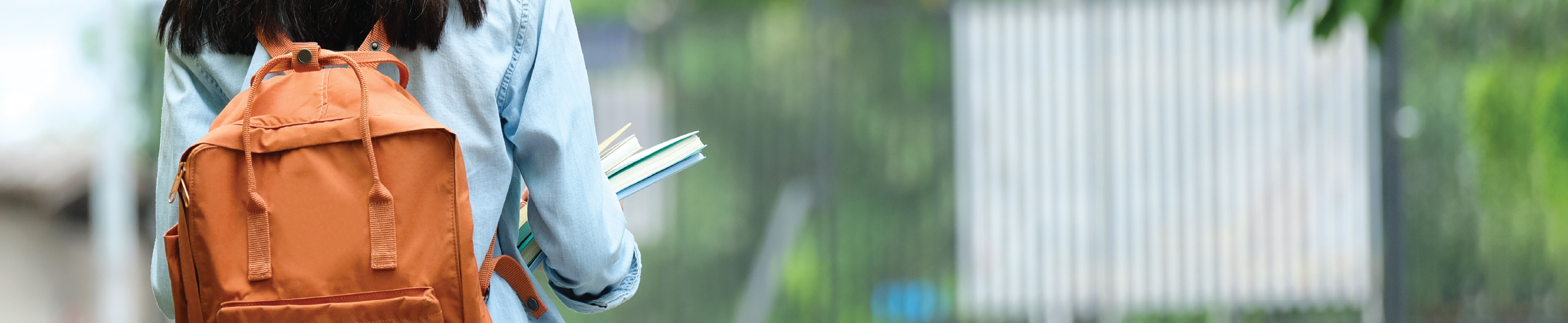 A female student wearing a backpack and holding books.