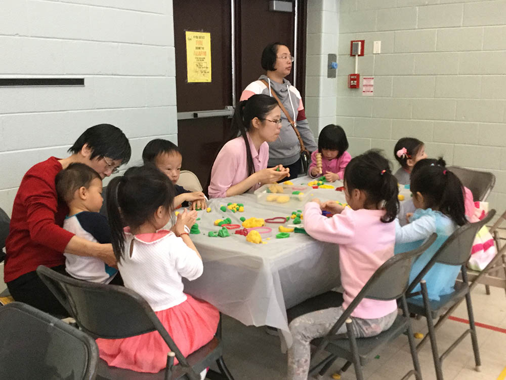 A group of children and 3 adults working on an activity during an Asian Canadian Heritage month event.