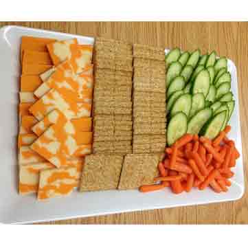 A cheese plate with healthy veggies and crackers