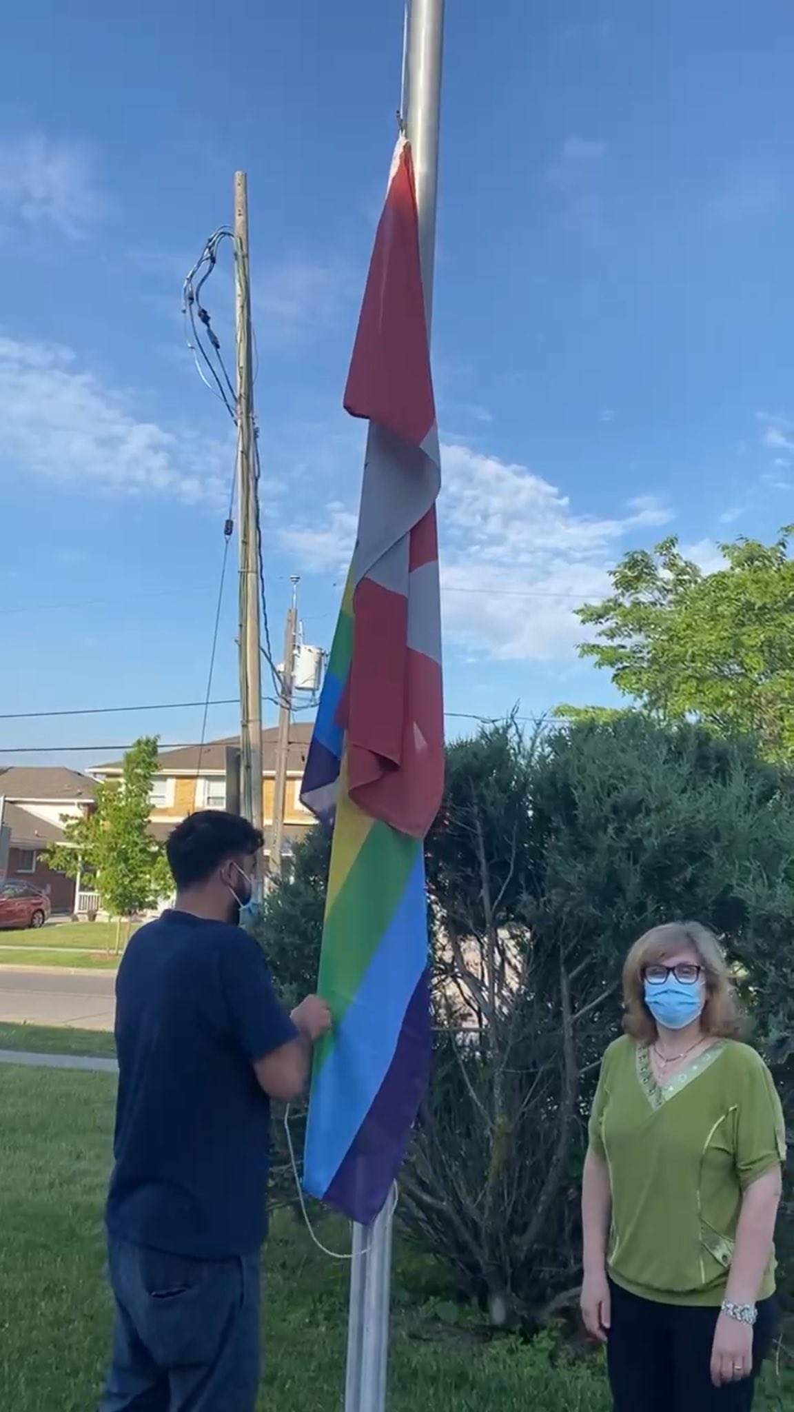 	St. Jerome Catholic School Pride Flag Attached to Canadian Flag Pole. Photo of Custodian and Staff.