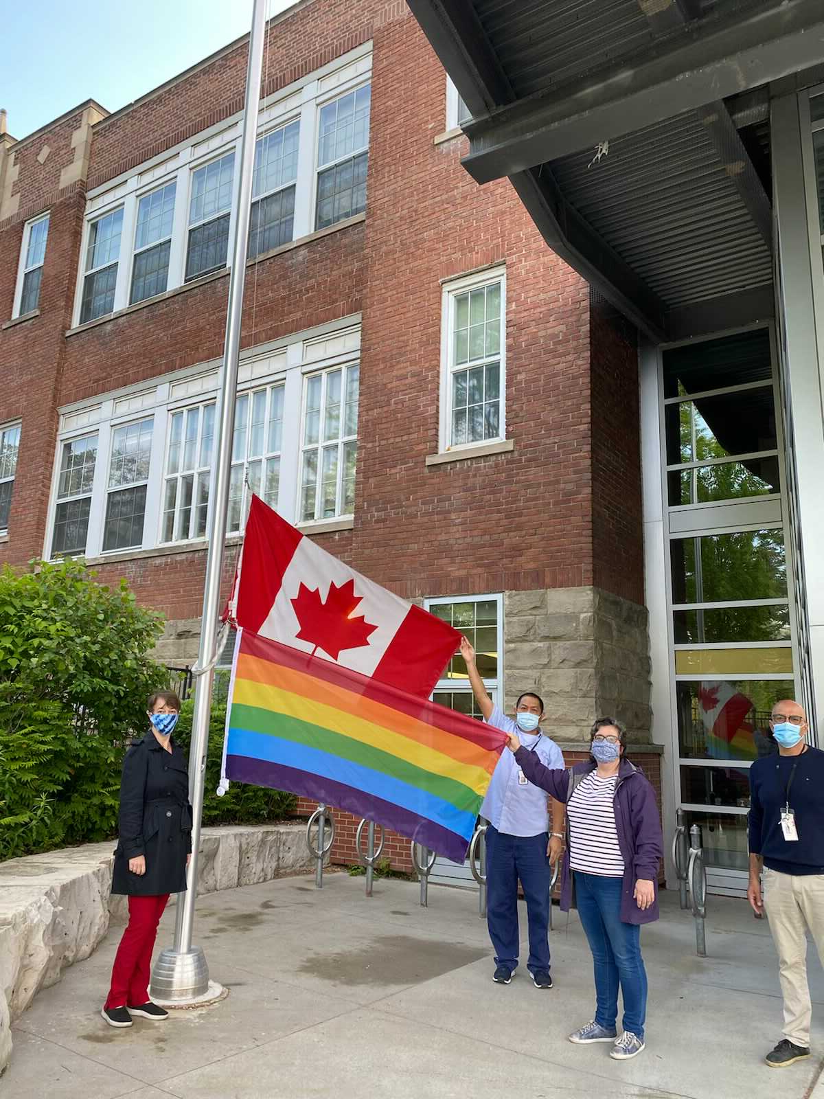 St. Pius X Catholic School Principal, Custodian, Staff and Community Members Raising the Pride Flag.