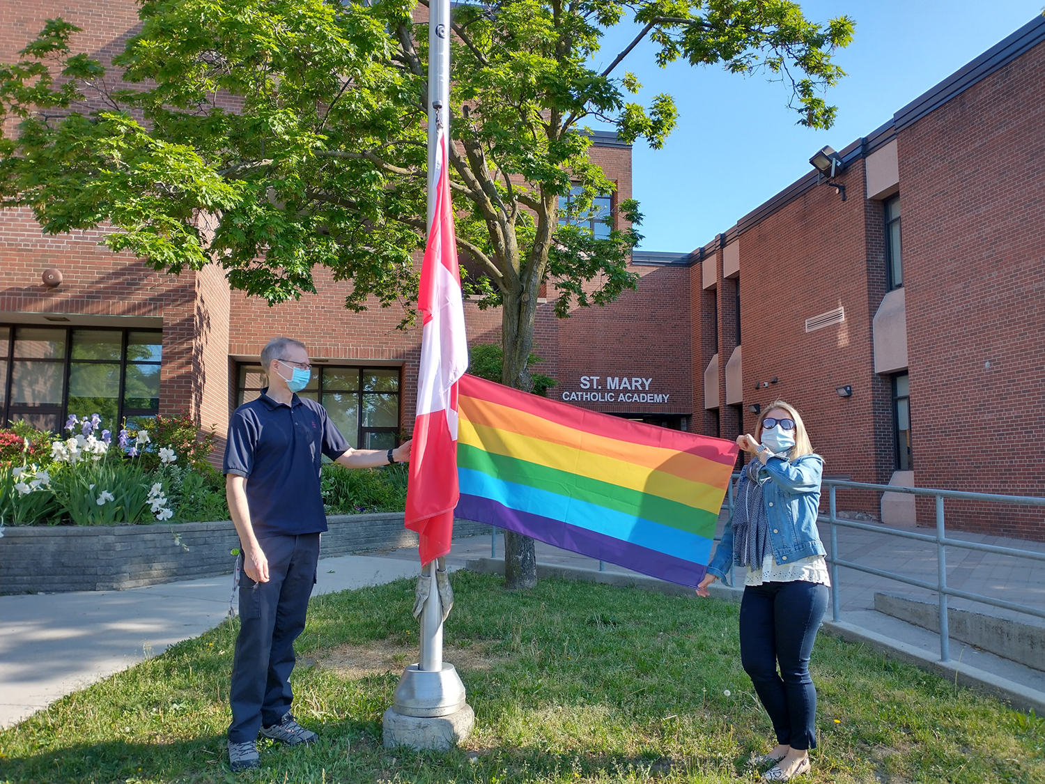 St. Mary Catholic Academy Principal and Custodian Raising the Pride Flag.