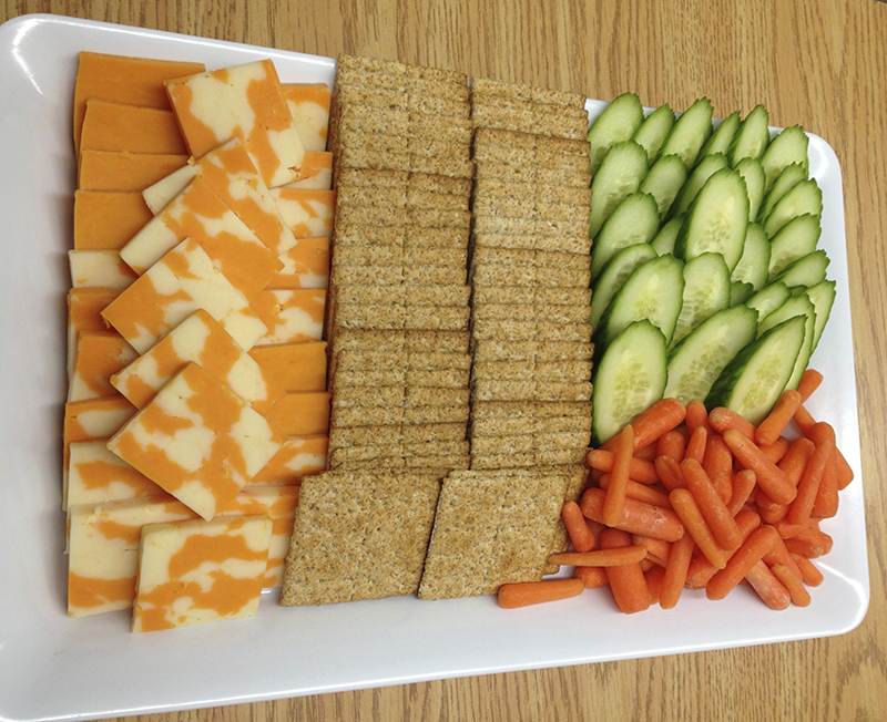A cheese plate with healthy veggies and crackers