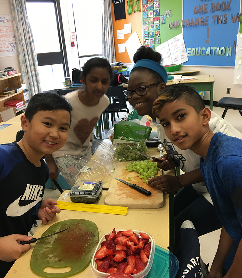 Students gathered around cutting board preparing food