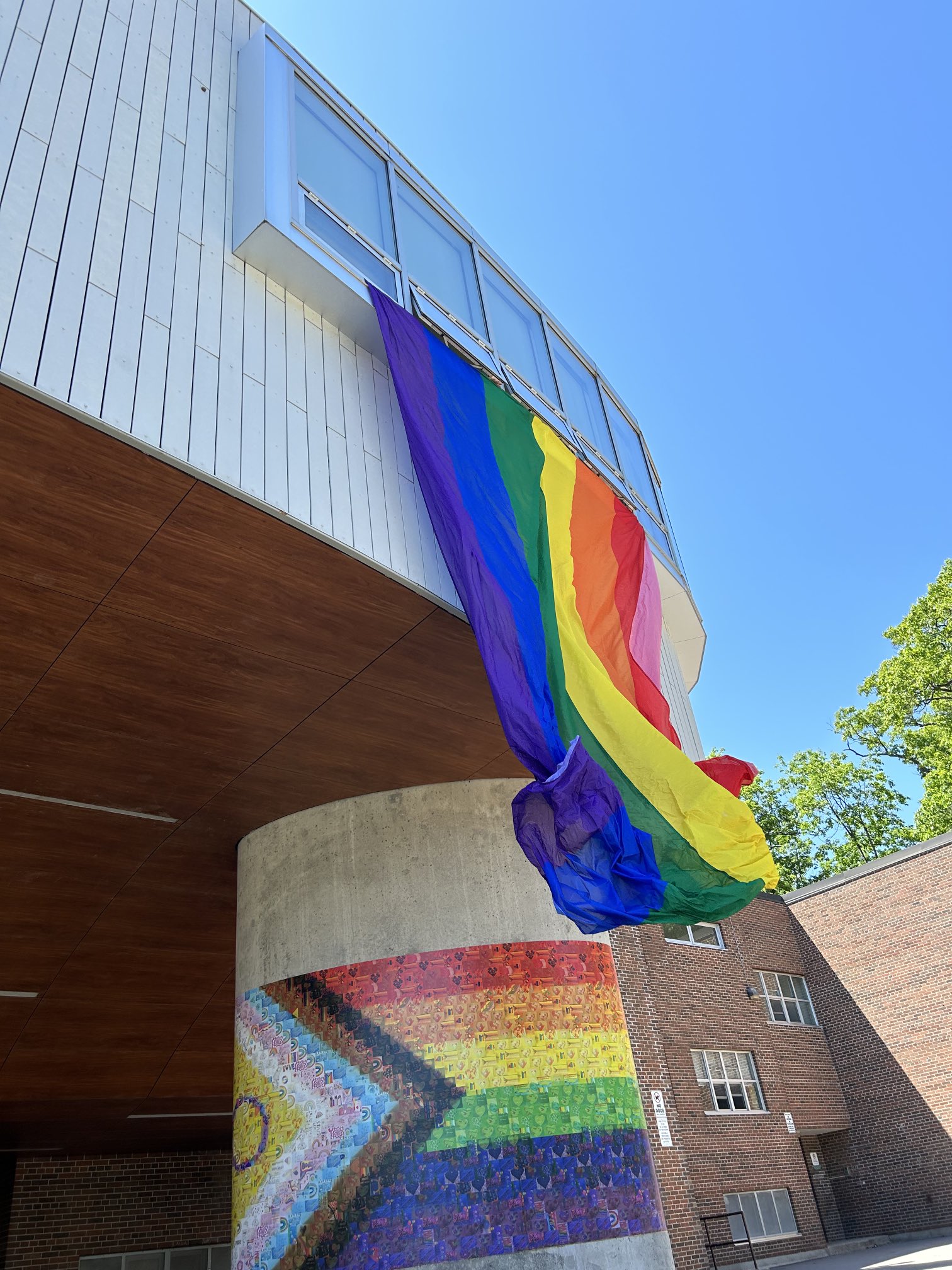 A picture of a Pride flag hanging outside of a school.
