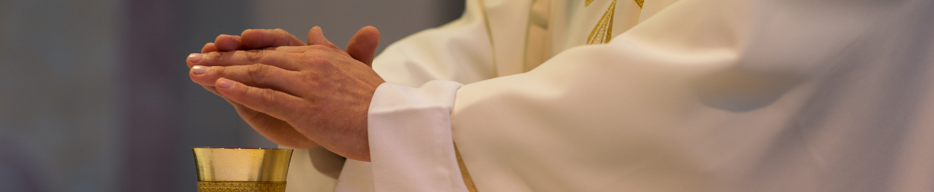 Priest consecrating chalice during mass