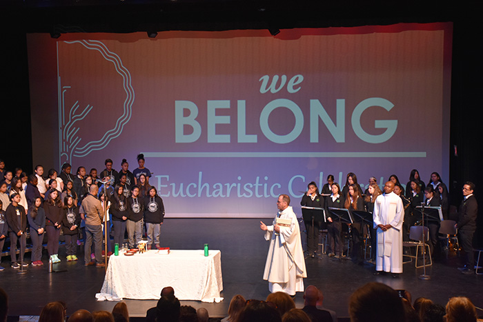 A priest speaking on stage at the we Belong Launch Celebration