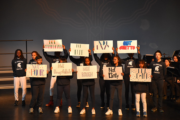 Students holding signs on stage at the we Belong Launch Celebration