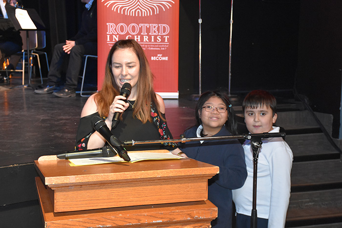 An adult and two students speaking at a podium at the we Belong Launch Celebration
