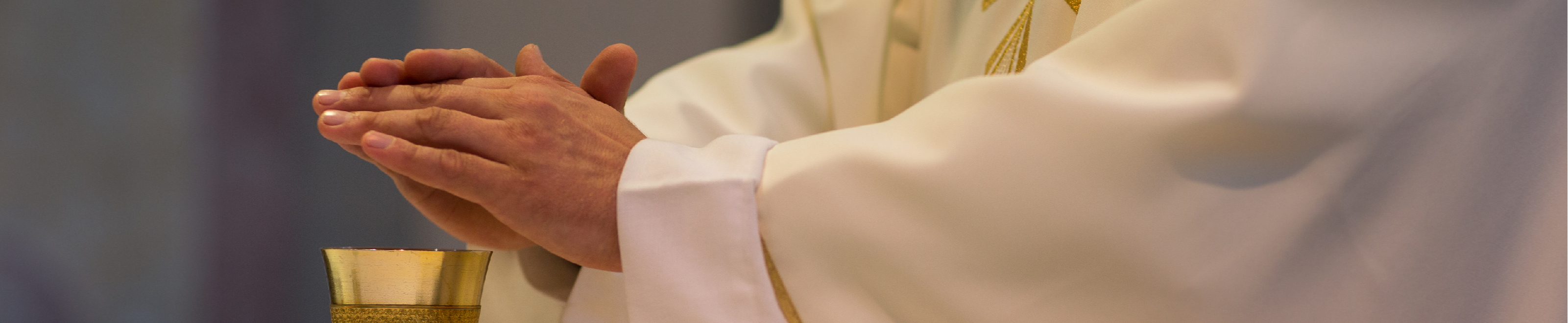 Priest consecrating chalice during mass.