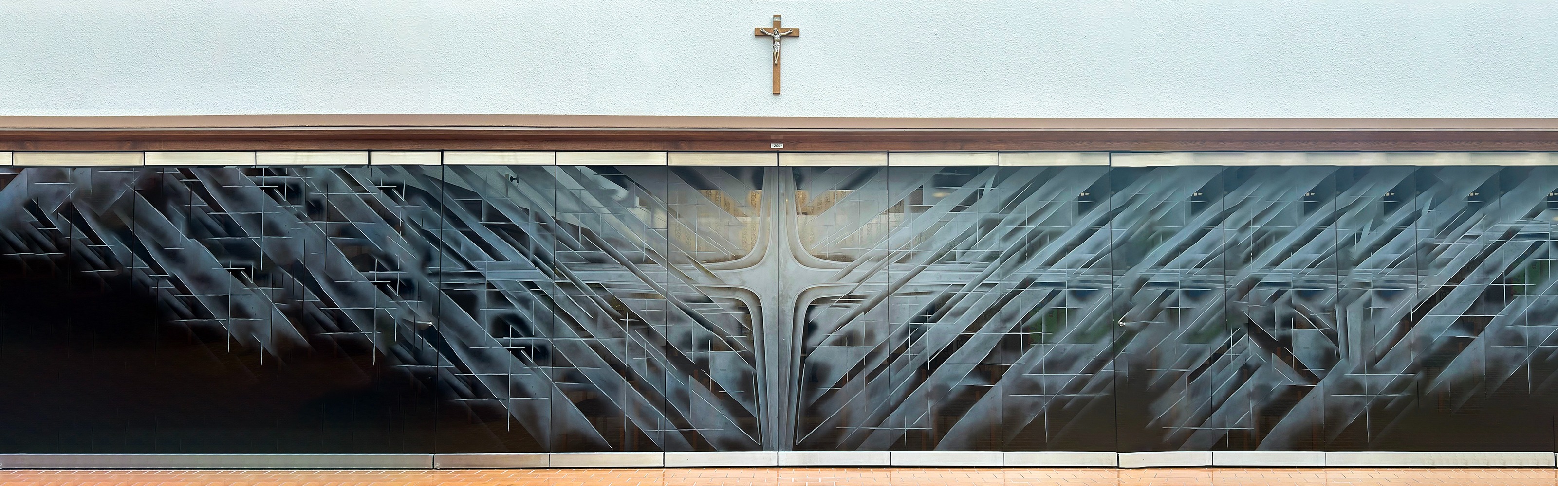 Photo of the glass prayer room door at the CEC with the glass frosted in designs of crosses, along with a statue of Jesus on the Cross on the wall above