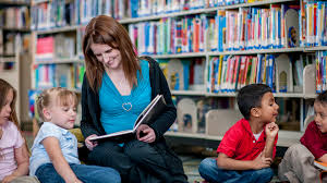 Teacher in library four students on the floor