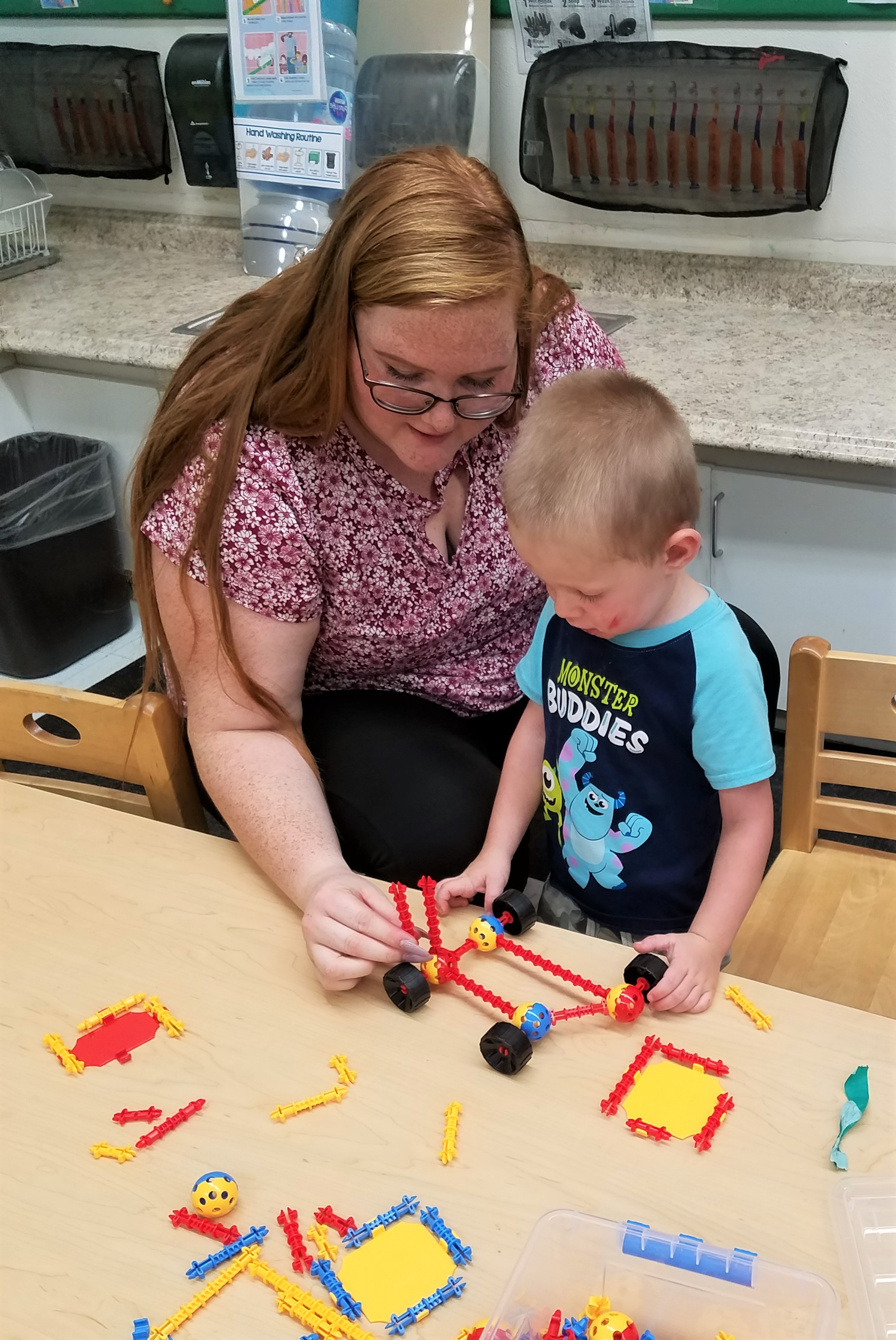 teacher helping child with a craft