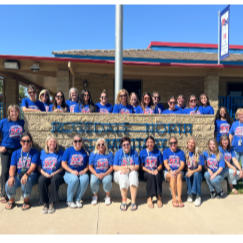 staff from Rosedale north sitting in front of, standing next to, and behind the Rosedale North Elementary school sign. All are wearing blue shirts