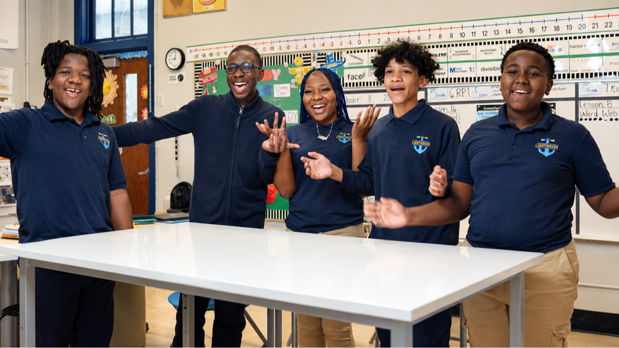 Five Lighthouse students smiling and laughing together in a classroom.