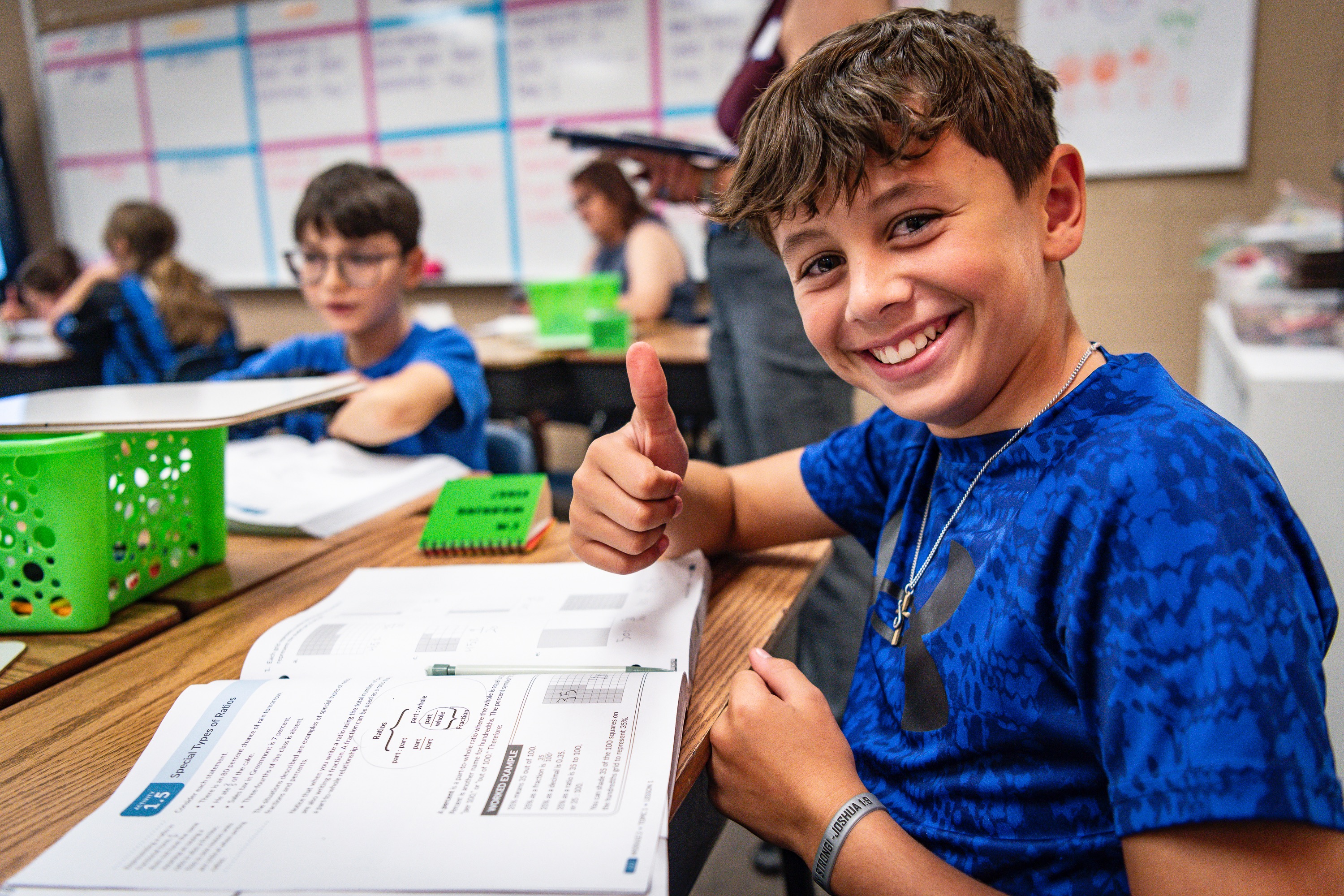A student gives a thumbs up while working on a math assignment