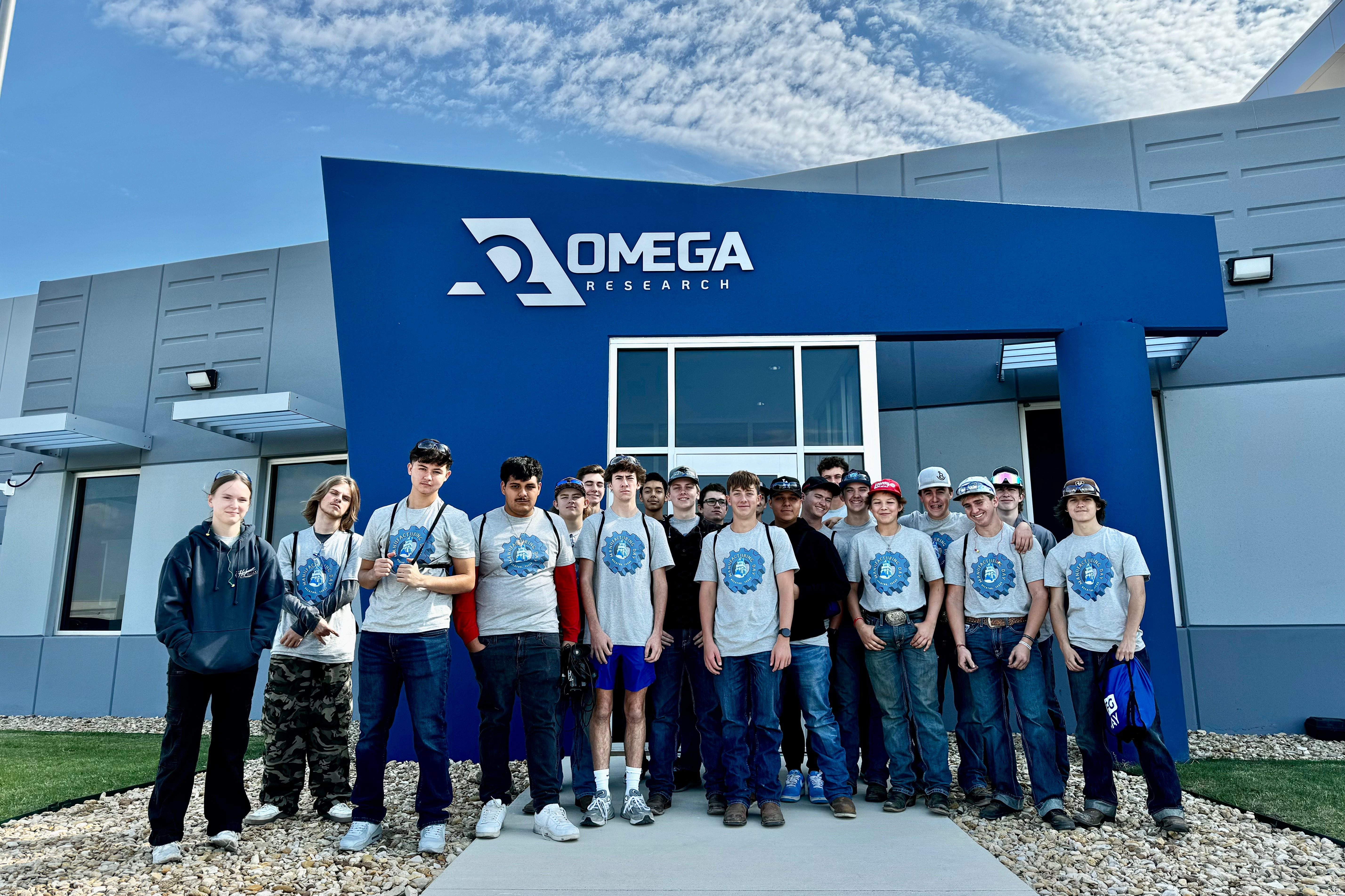 Students pose for a photo in front of Omega Research for the 2024 Manufacturing Day