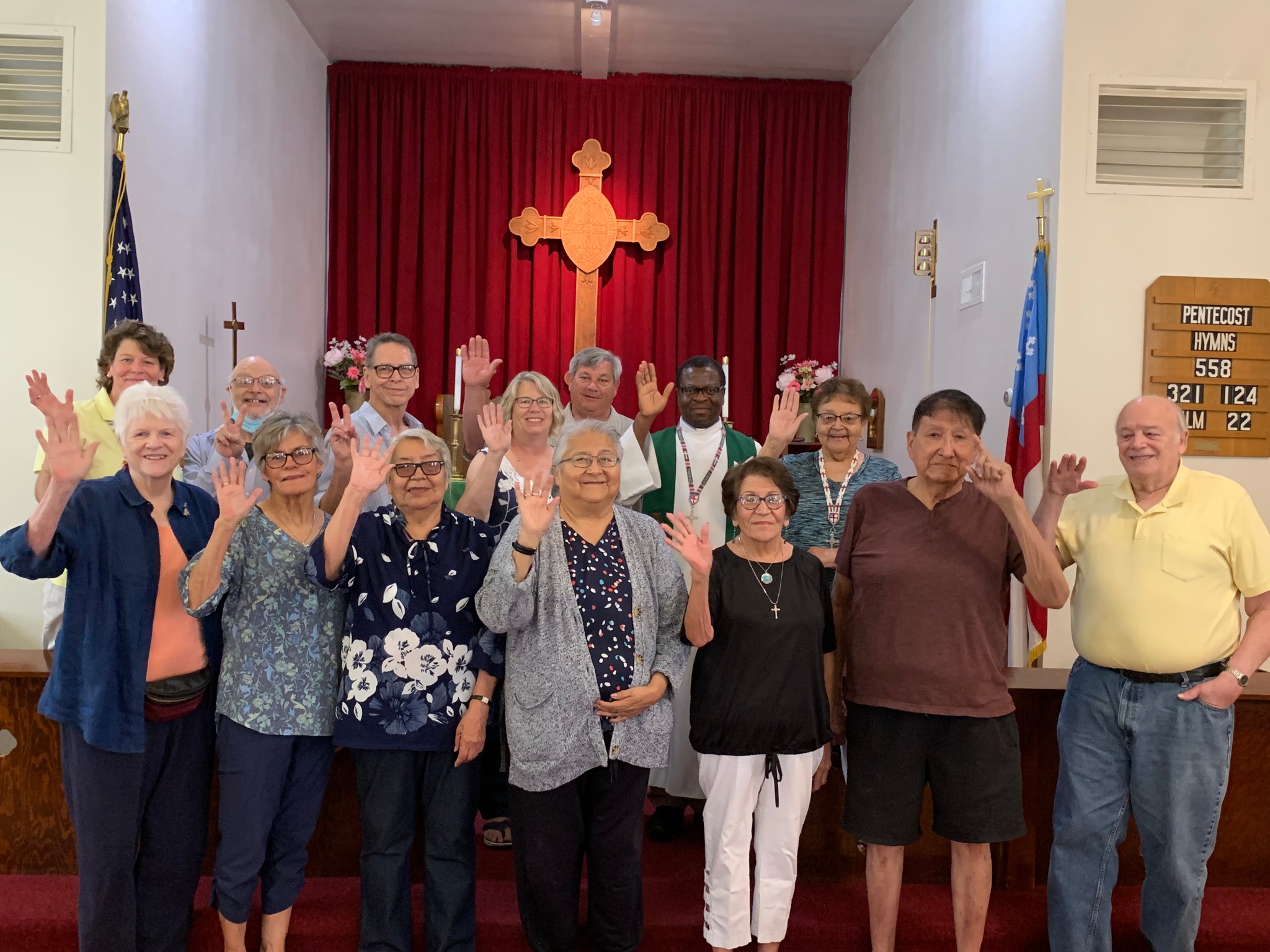 Church members standing and waving in front of the altar