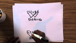 Hand solving math equations on white paper