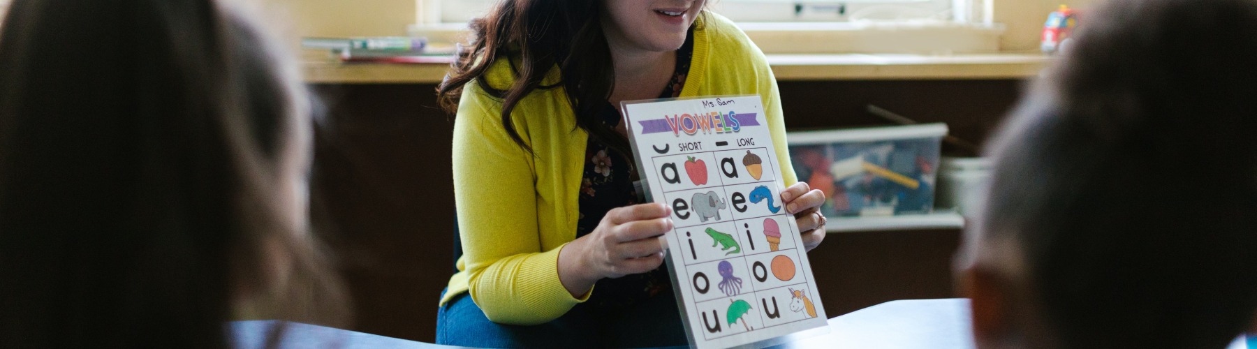 teacher holding phonetic alphabet chart
