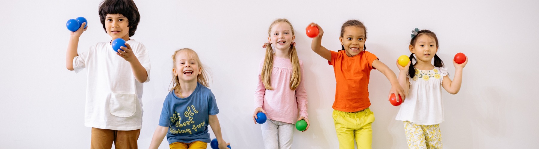 students holding colorful balls and smiling