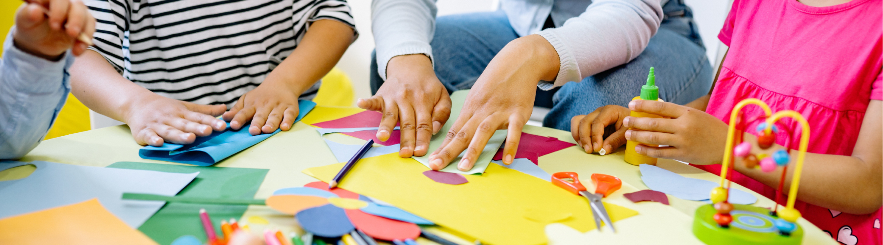 students cutting and folding construction paper on arts and crafts table