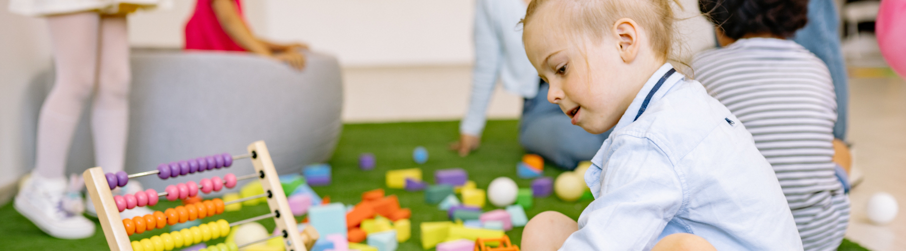 Child using abacus in playroom of other children