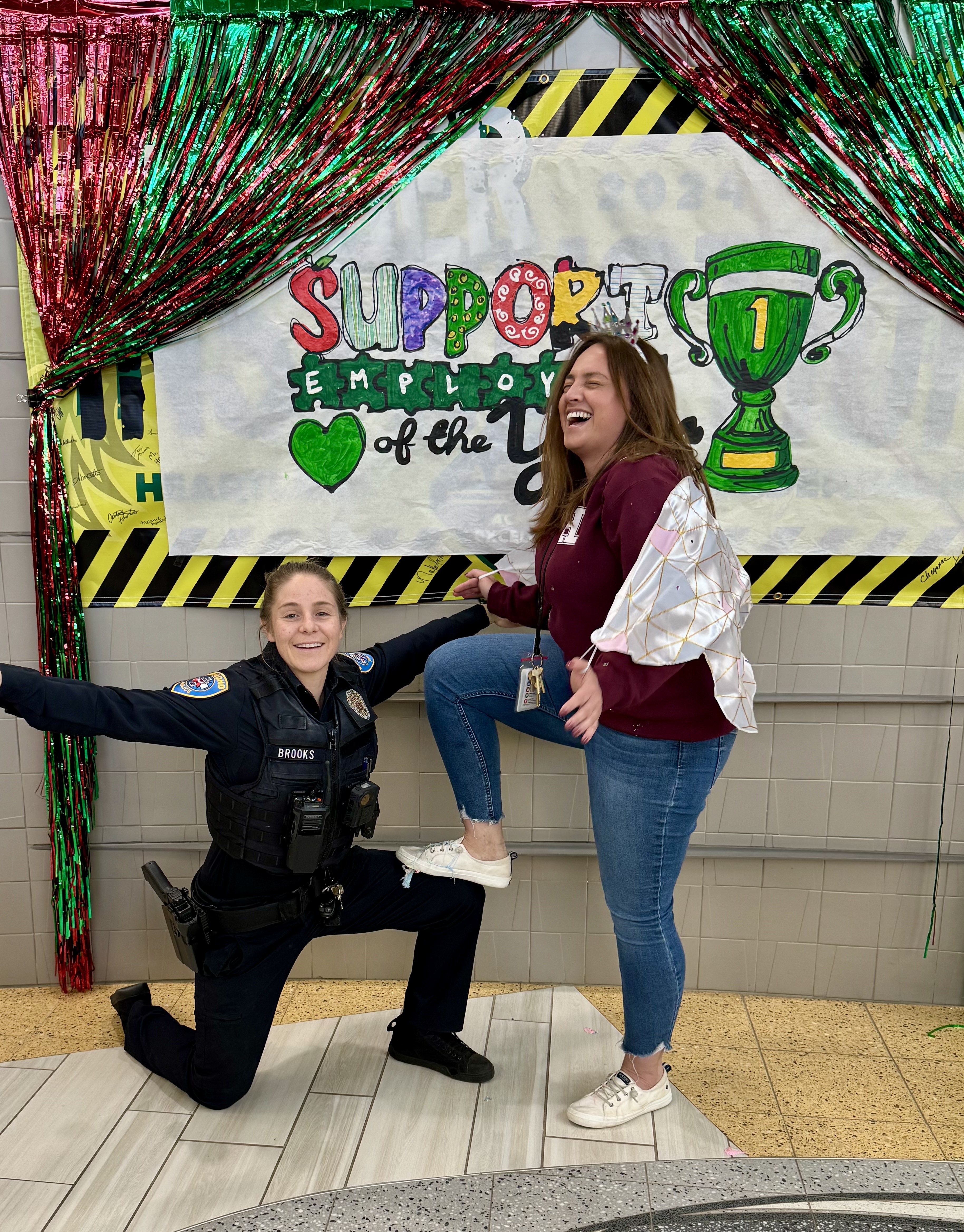 Officer Amy Brooks on one knee with her arms raised up and Cheryl Thatcher has her foot resting on Amy's knee