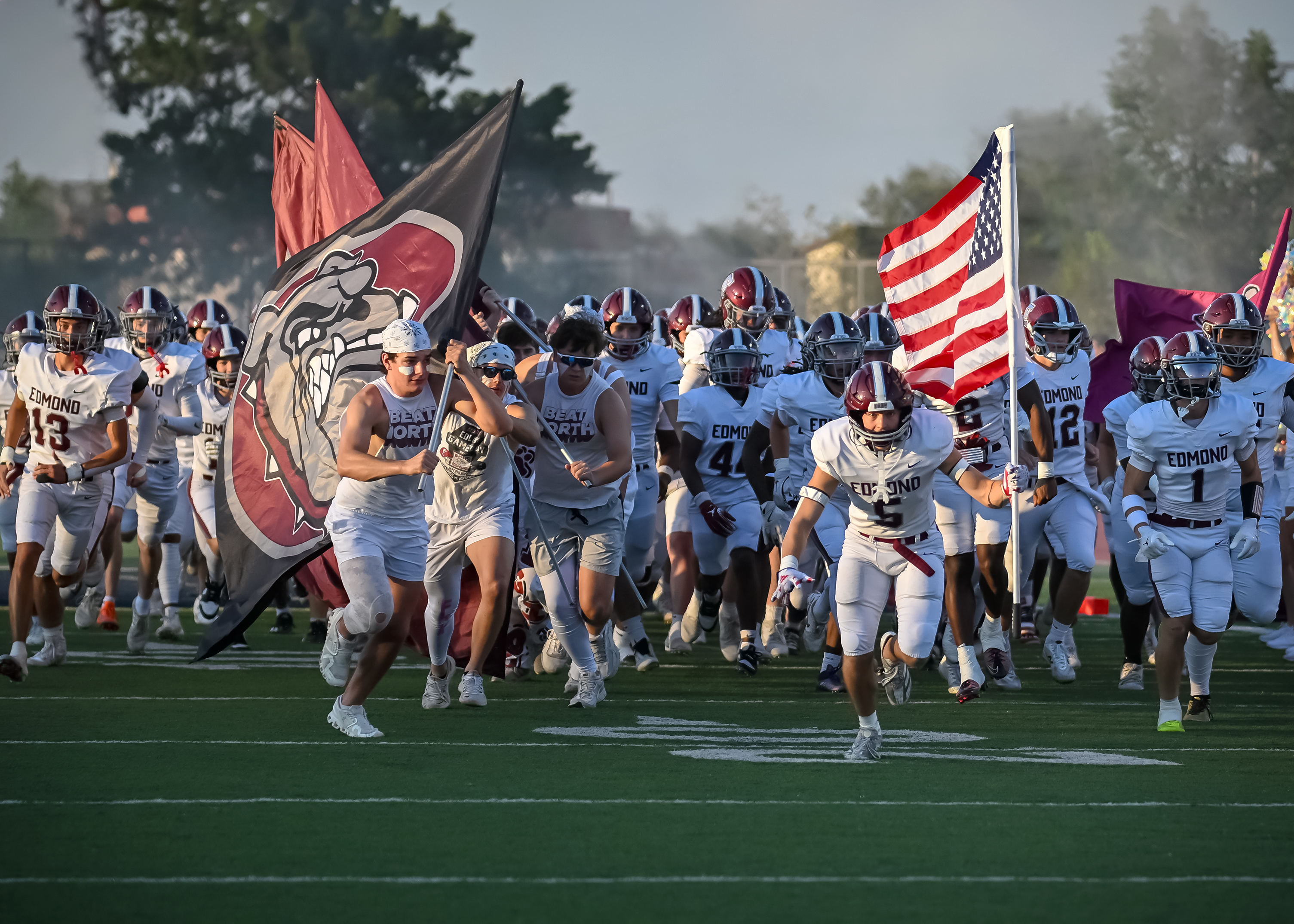 Football team and student section leaders running with flags at game