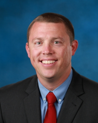 man wearing black jacket, blue shirt and red tie