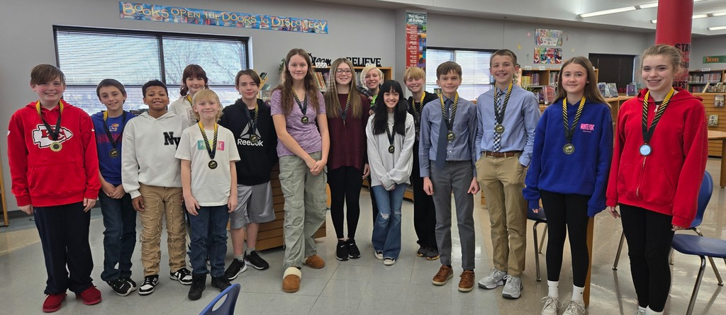 middle school students standing  a line wearing spelling bee medals