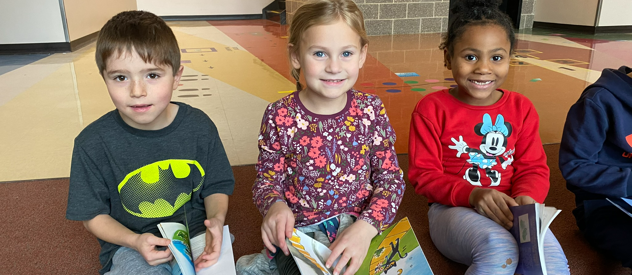 first graders sit on the learning stairs holding paperback books