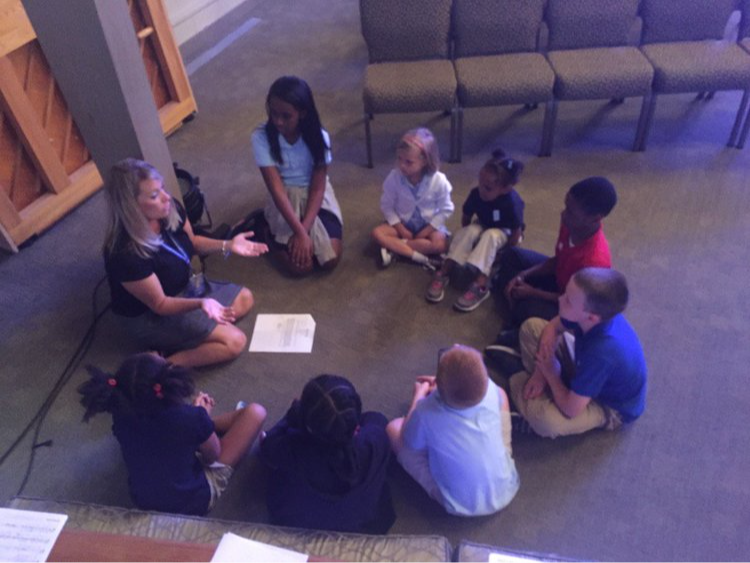 Groups of students and a teacher sitting in a circle 