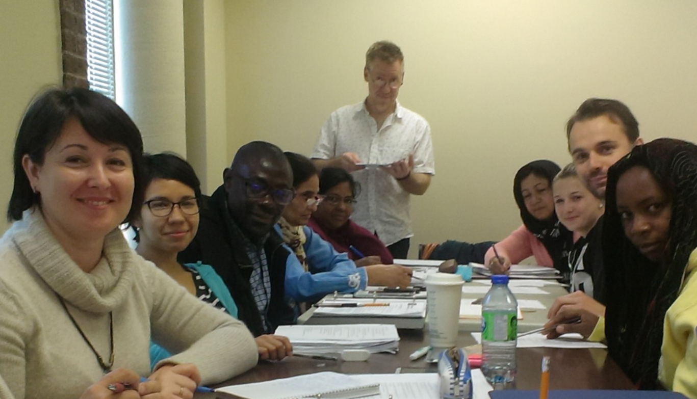 Adult ESL classroom attendees at library table smiling for picture