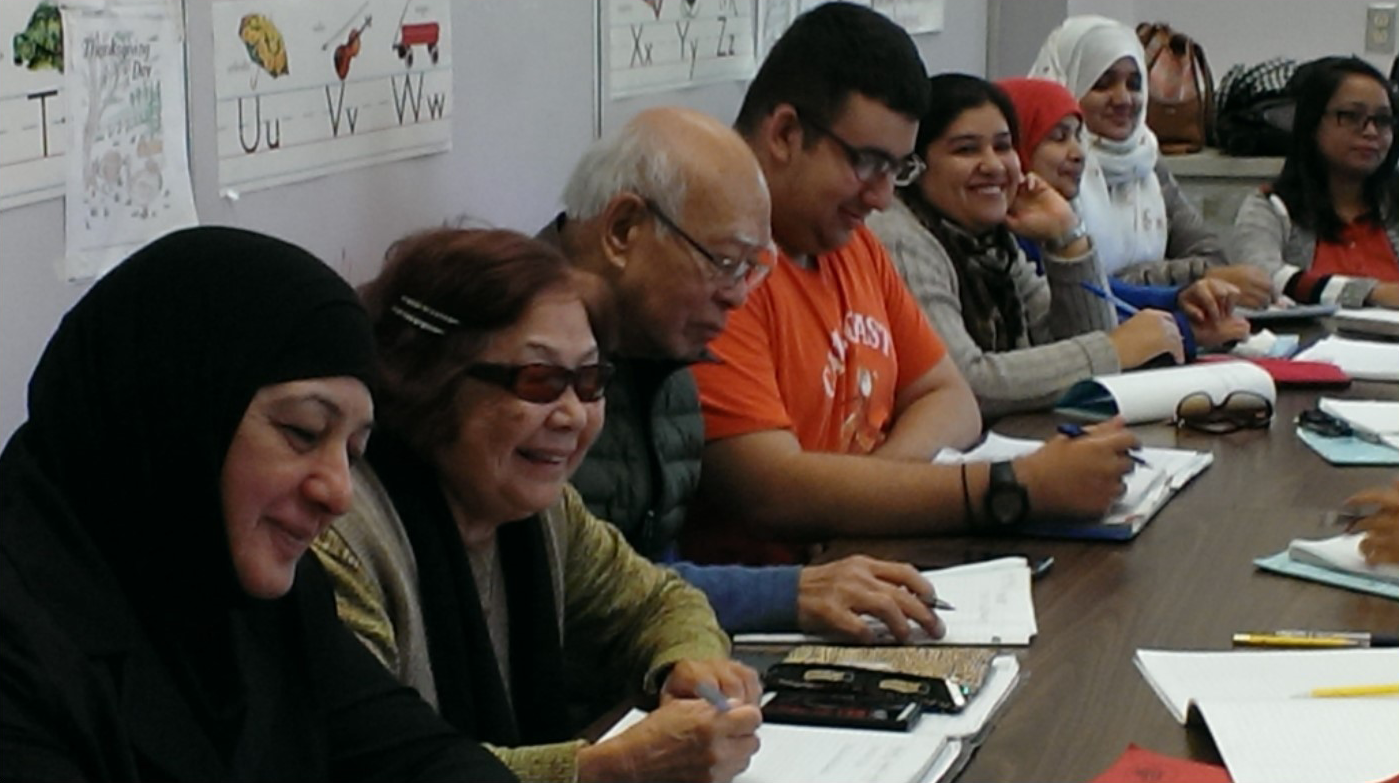 row of adult ESL classmates laughing and writing in notebooks