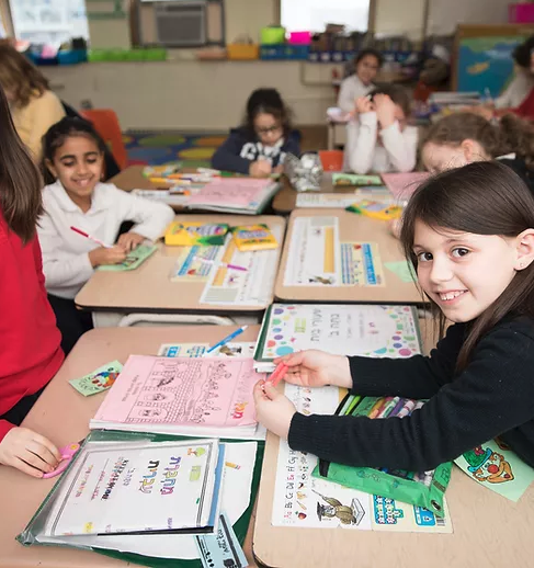 students in classroom sitting and doing writing activities at desks