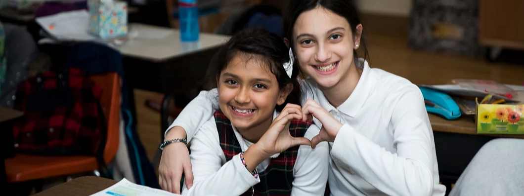 two girls making a heart with their hands