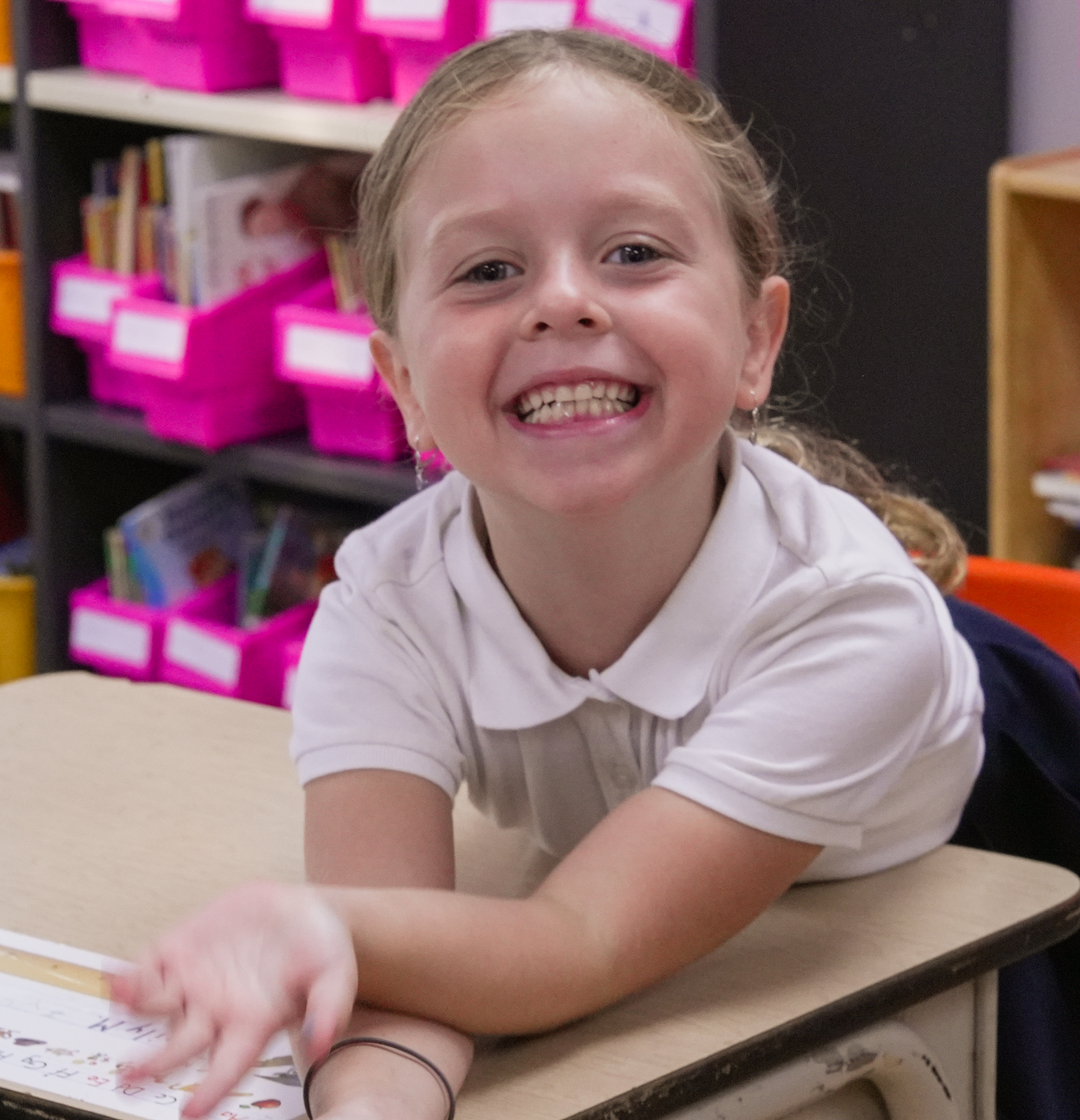 Student writing at a desk and smiling