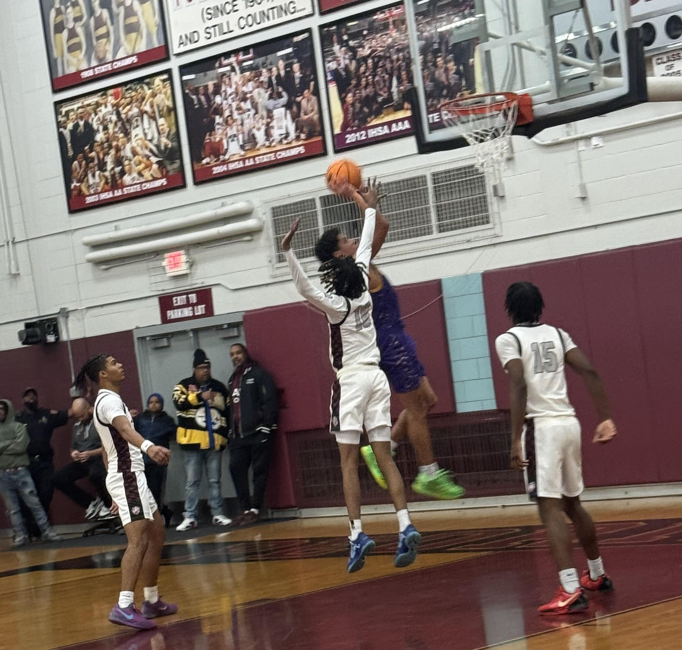 AJ Evans (Center) goes up to block a shot as Spencer Russell (left) and Fenix Foy (right) get ready for a rebound.