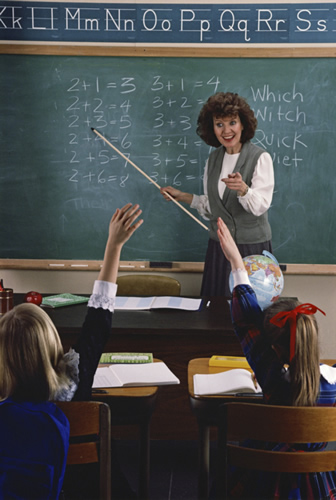 A teacher pointing to a chalkboard