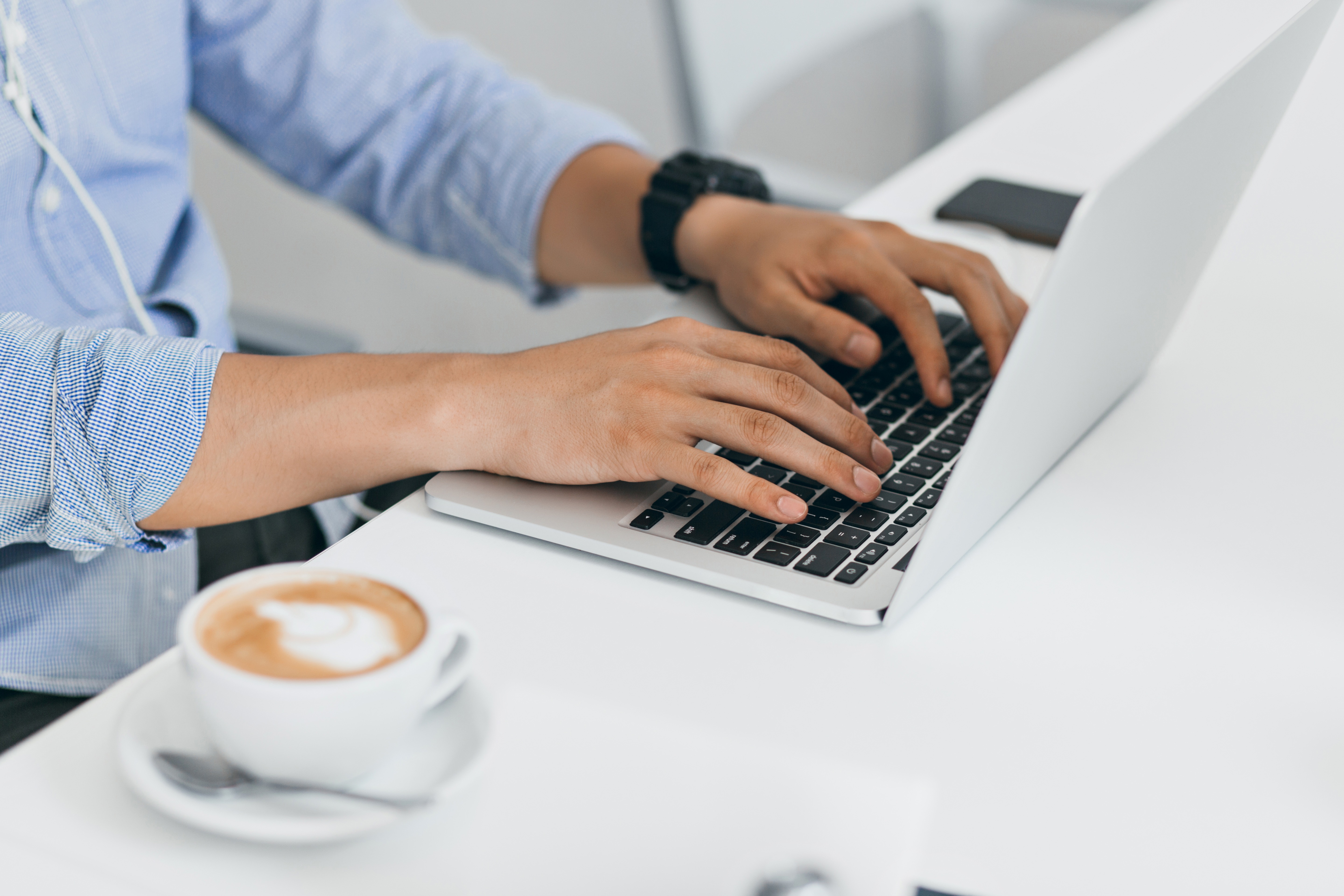 man's hands on computer with coffee cup