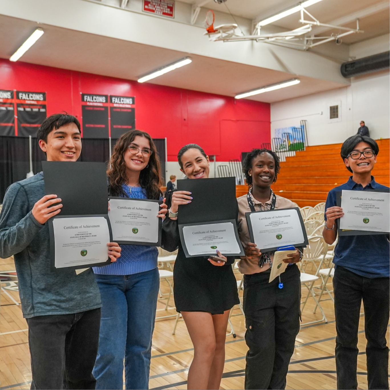 Kids smiling holding there reclassification english proficiency certificates.