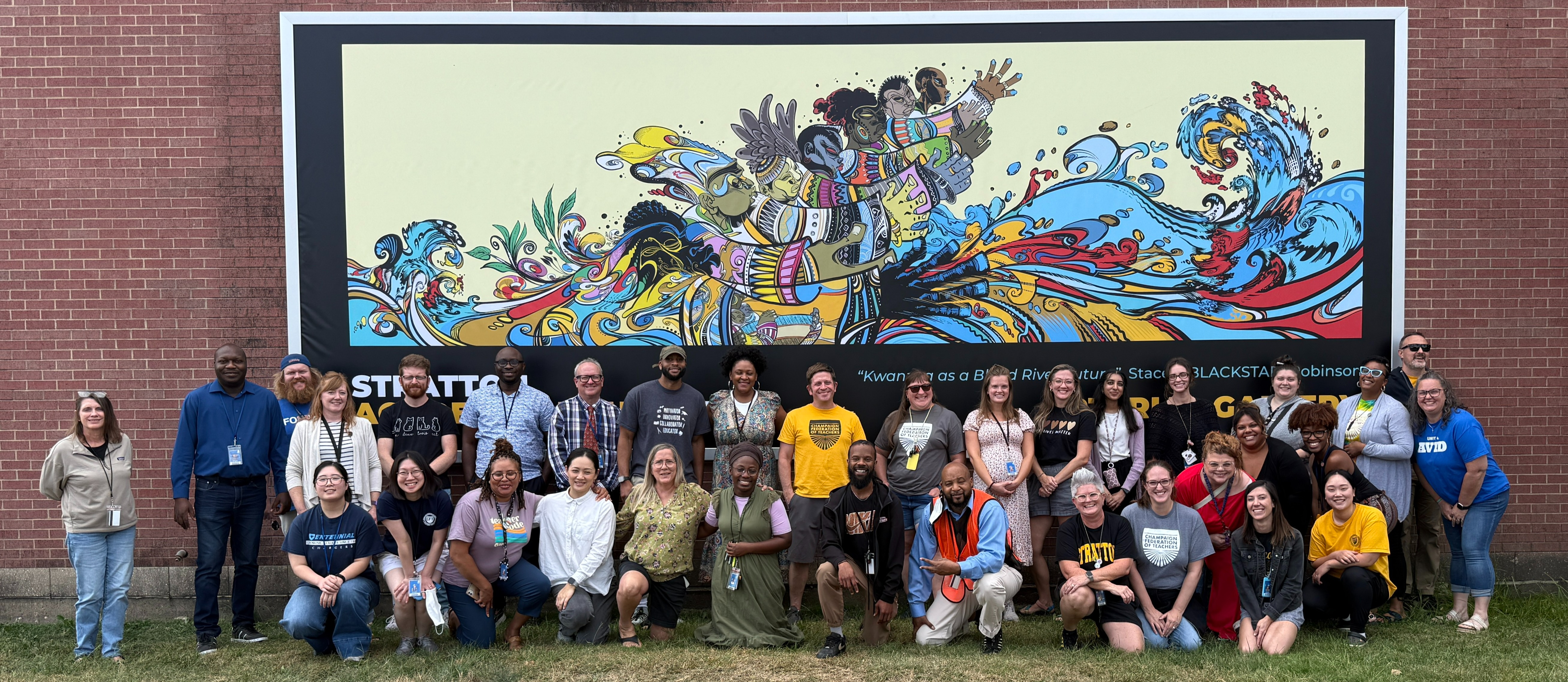 stratton academy of the art staff pose in front of colorful mural outside of schools