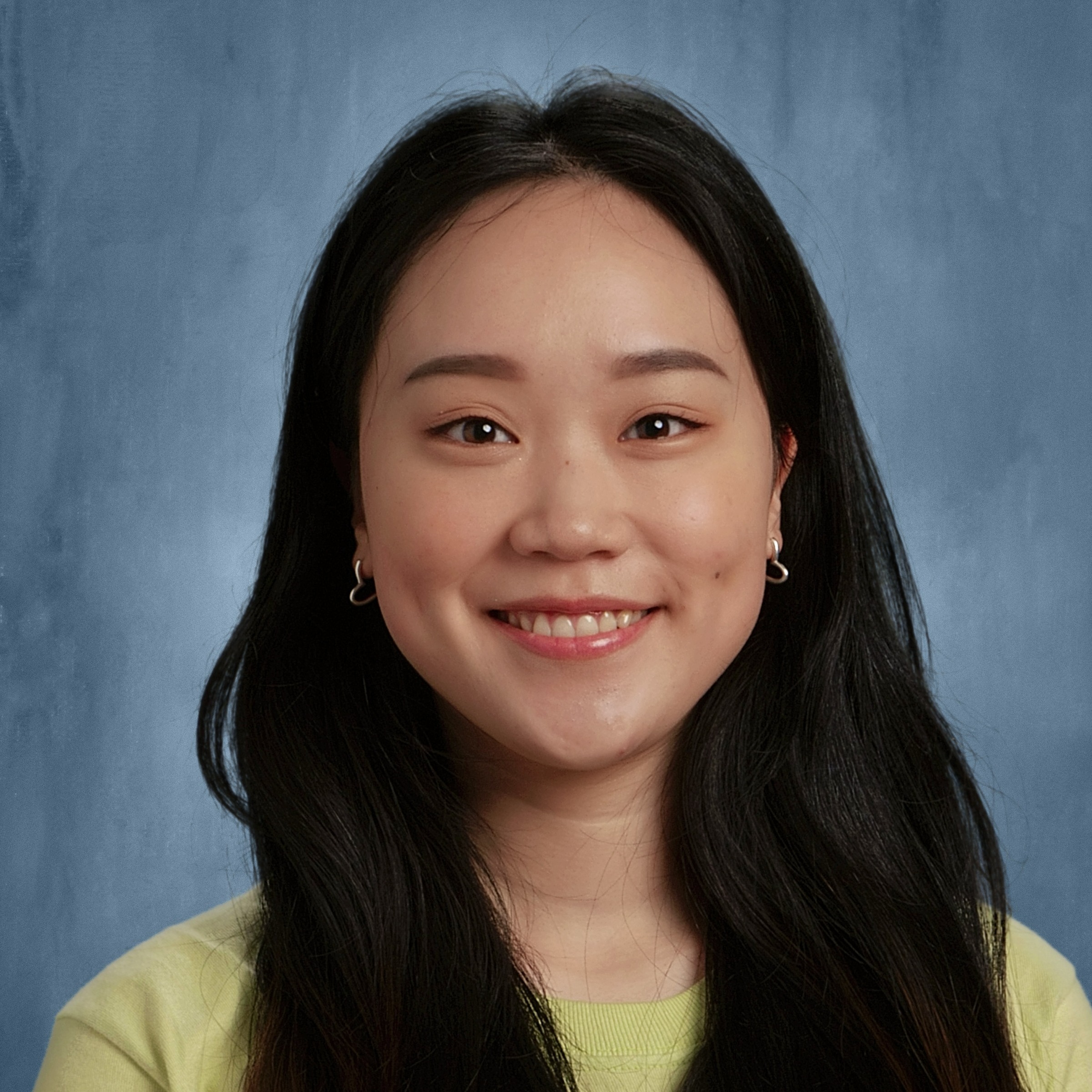 Smiling young woman with dark, straight hair wearing butter-yellow shirt