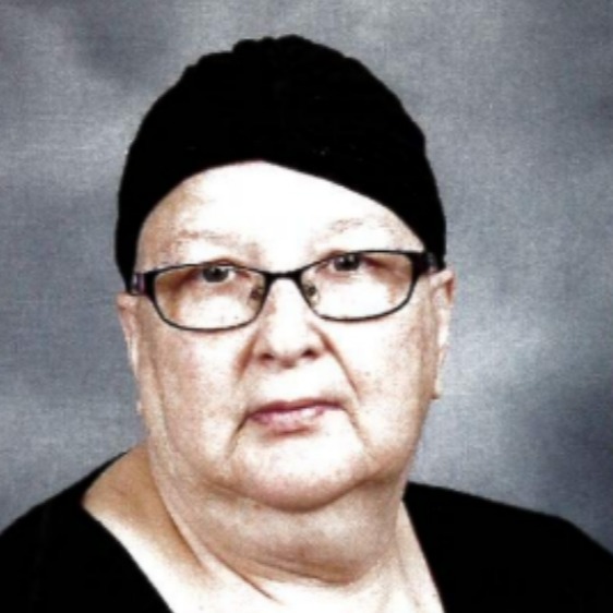 Woman wearing glasses and black head covering, looking directly at camera